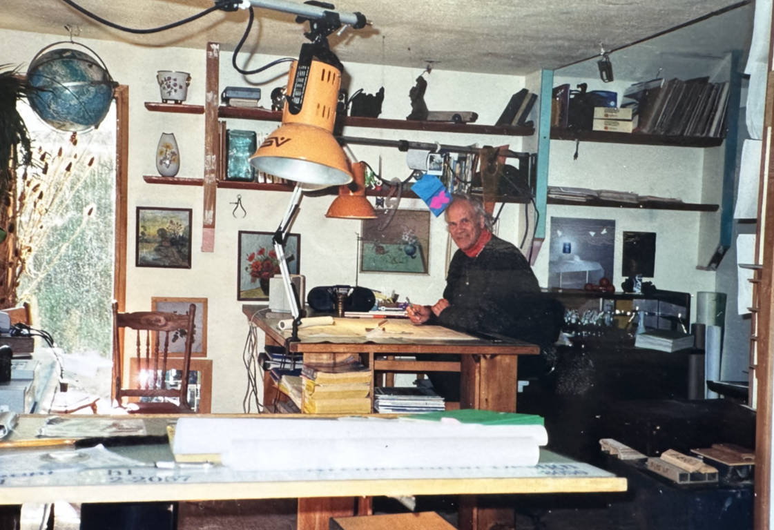 Bent amidst his drawing tables and lamps